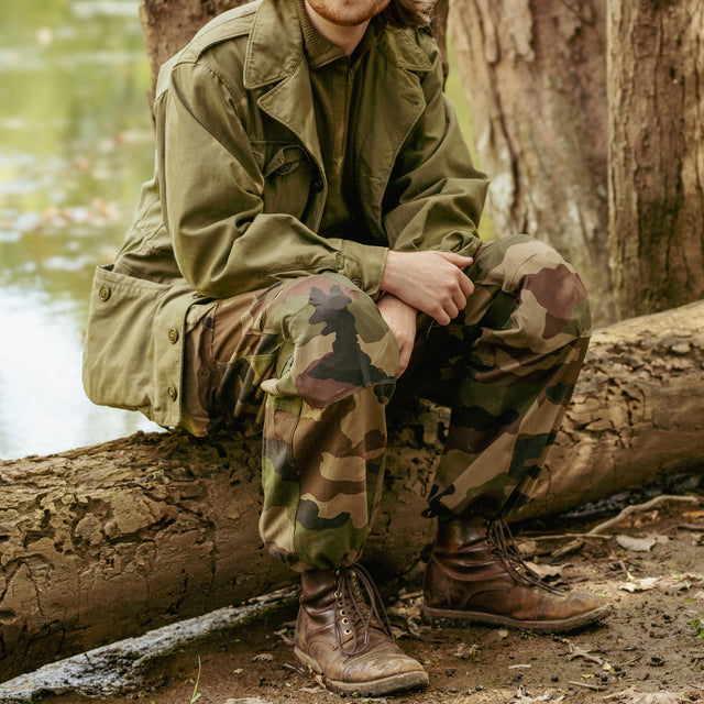 Man sitting down on a log while wearing French Army Combat Pants