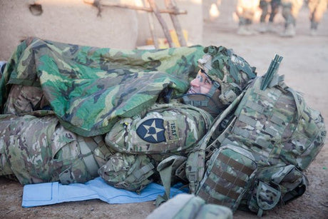 Soldier laying down while using woobie as a blanket